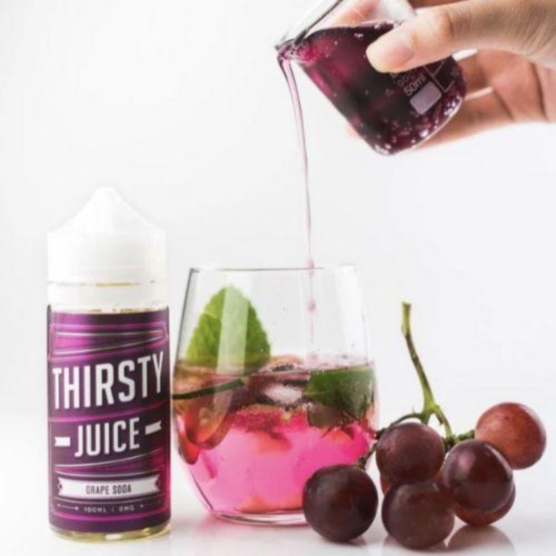 Thirsty Juice Co | Grape Soda | 100ml bottle with grape juice being poured from another glass and 6 grapes on the vine